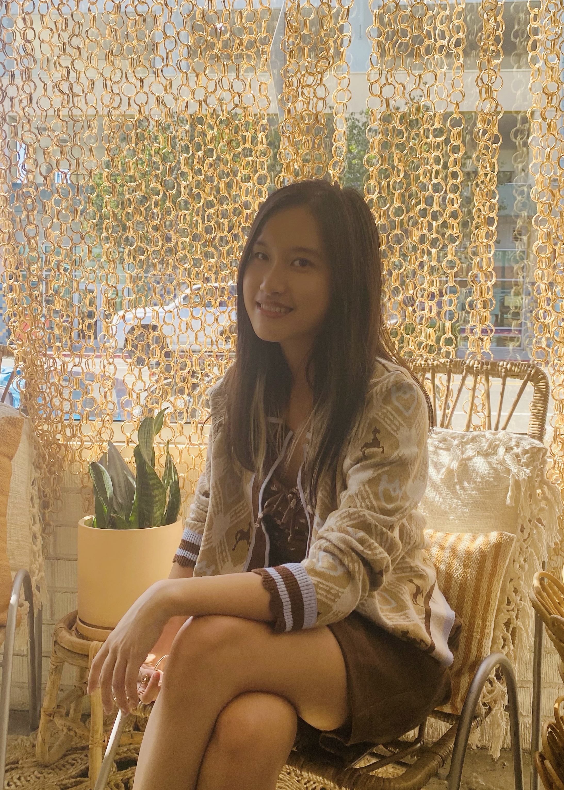 A profile photo of Mingyi: An Asian girl with long hair sits on a chair, wearing a brown outfit, and smiling at the camera.